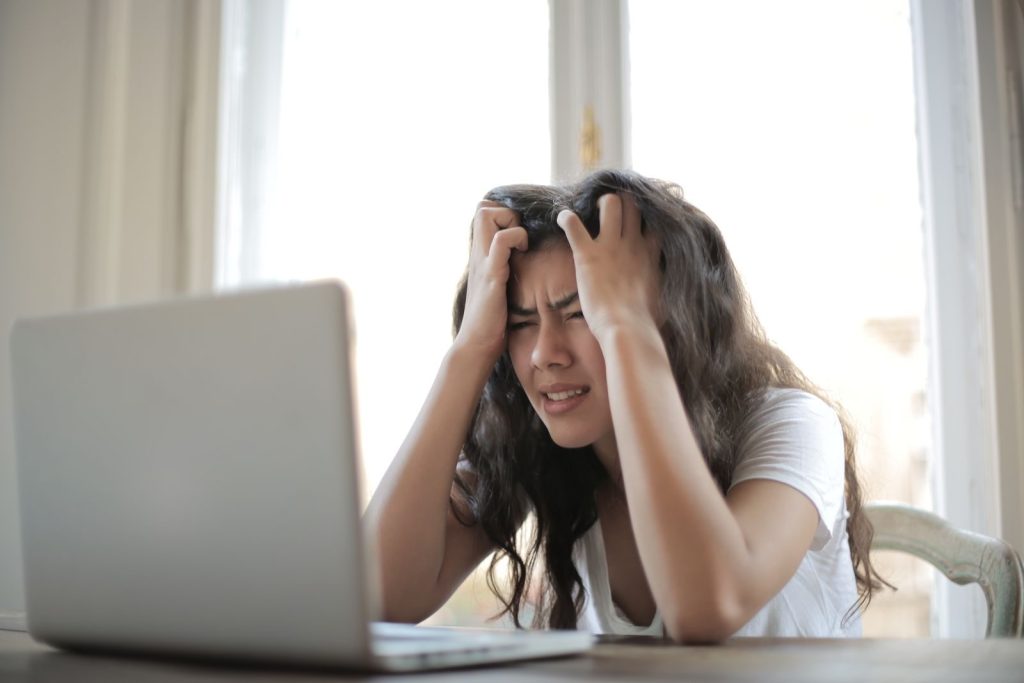Photo by Andrea Piacquadio Frustrated woman struggling with remote work stress and digital challenges indoors.